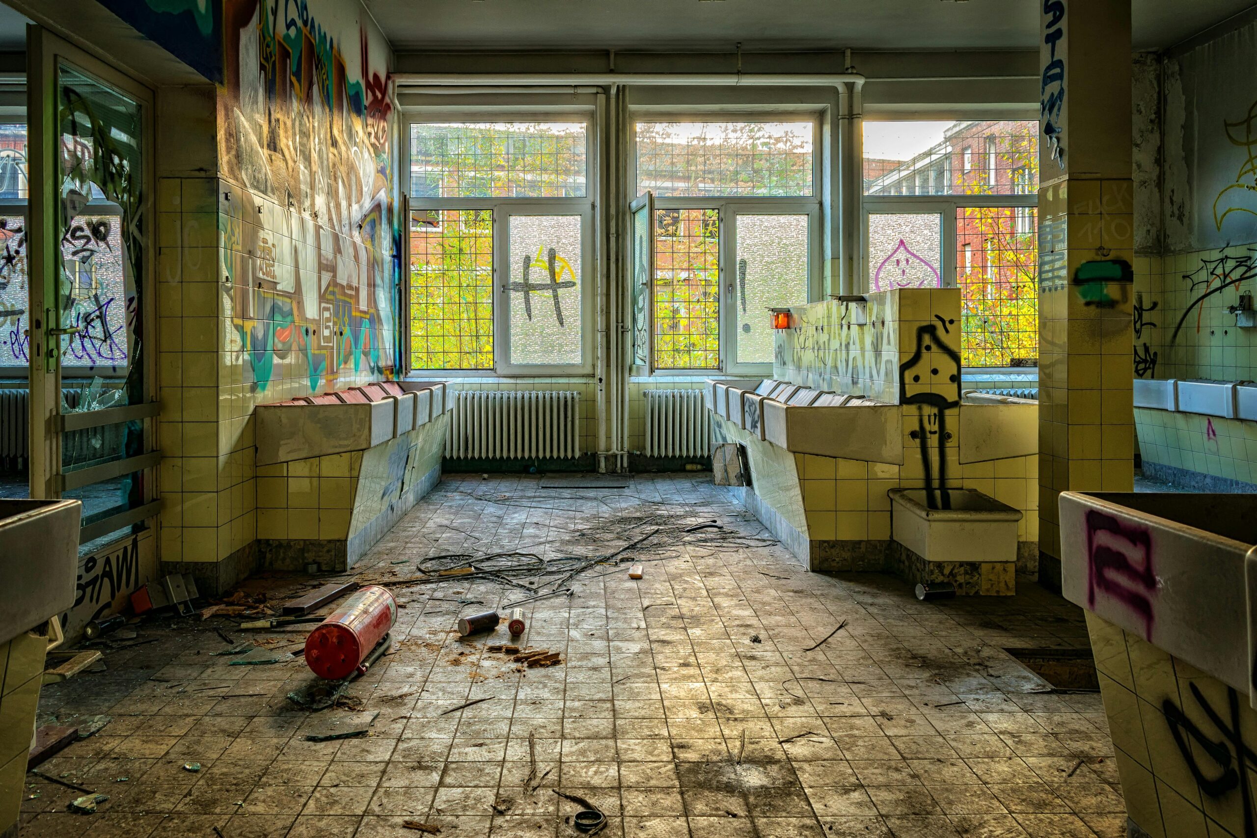 A broken window with shards of glass scattered around, illustrating the aftermath of vandalism