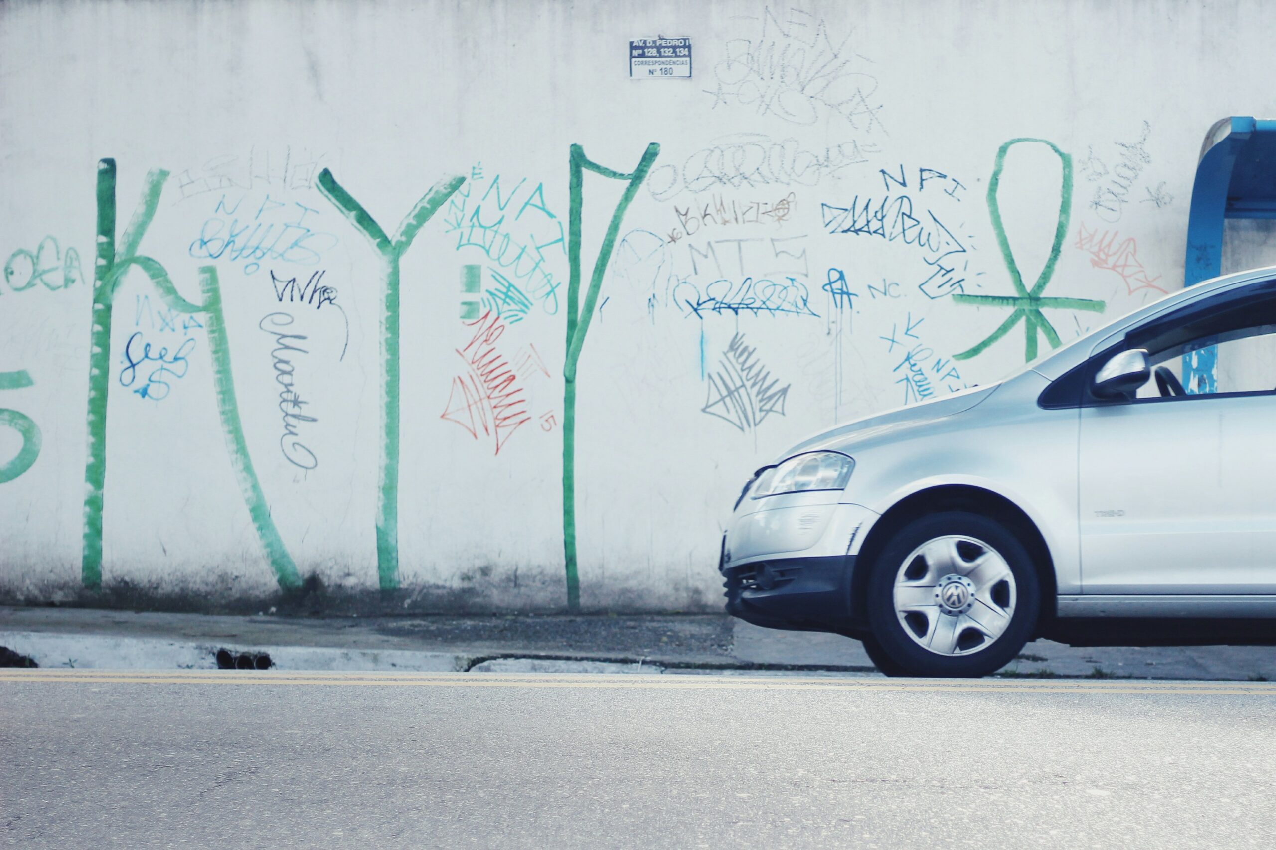 A car with scratches and dents due to vandalism in a dark alley