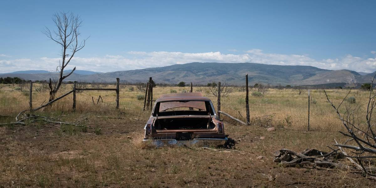 Abandoned 1965 Dodge Coronet in a dry field on a hot summer afternoon in Whiterocks, Utah, USA, August 14, 2023.