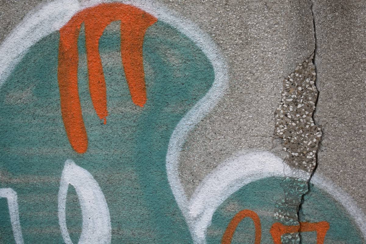 Graffiti decorates a textured concrete surface.