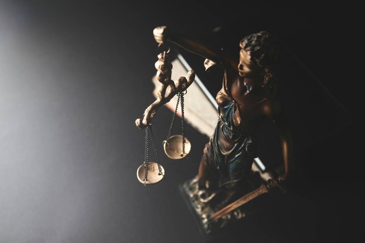 Statue of justice and scales of justice on a black background.